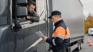 Polizeikontrolle eines LKW am Straßenrand, Kontrollbeamter prüft die Papiere des Fahrers